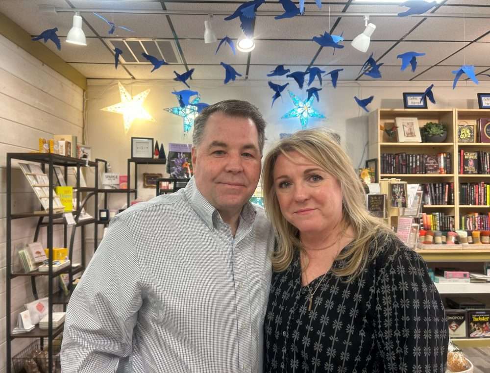 Kim and Rob Rickard, owners of Ten Trees Books, smile in front of the shelves and decor inside their store.
