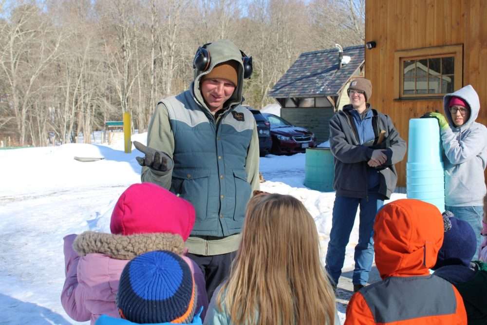 Casey Townsend, executive director of the Natick Community Organic Farm, tells his youngassistants about how they will hang buckets to collect maple sap on Feb. 12.